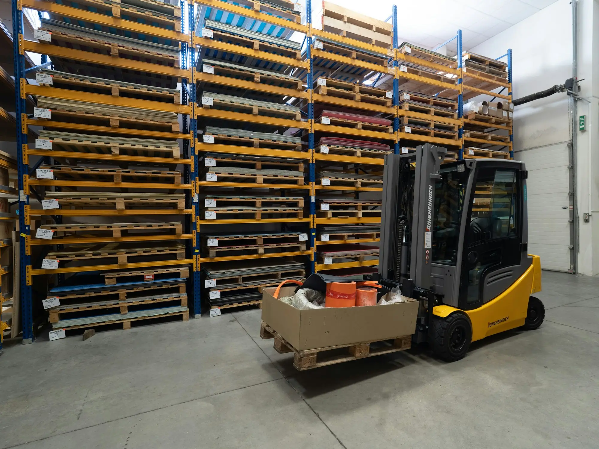 Yellow forklift carrying a pallet past racking inside a warehouse a business owner has bought