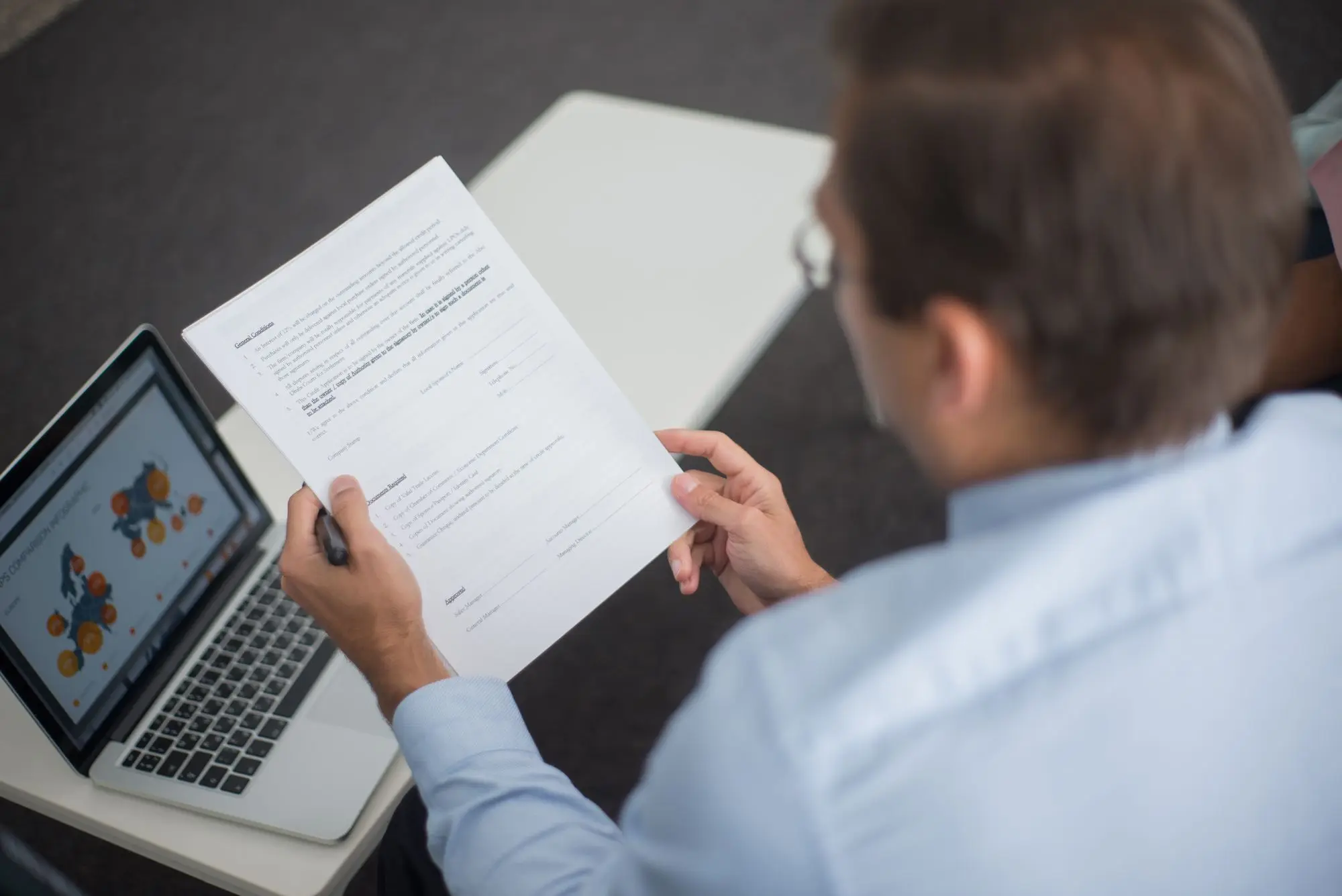 Business owner reading a payroll tax letter from the state revenue office beside a laptop